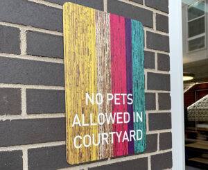 Colab Apartments exterior no pets allowed sign yellow pink purple and blue