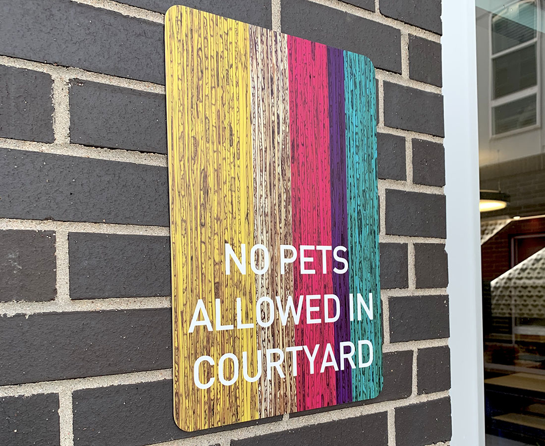 Colab Apartments exterior no pets allowed sign yellow pink purple and blue
